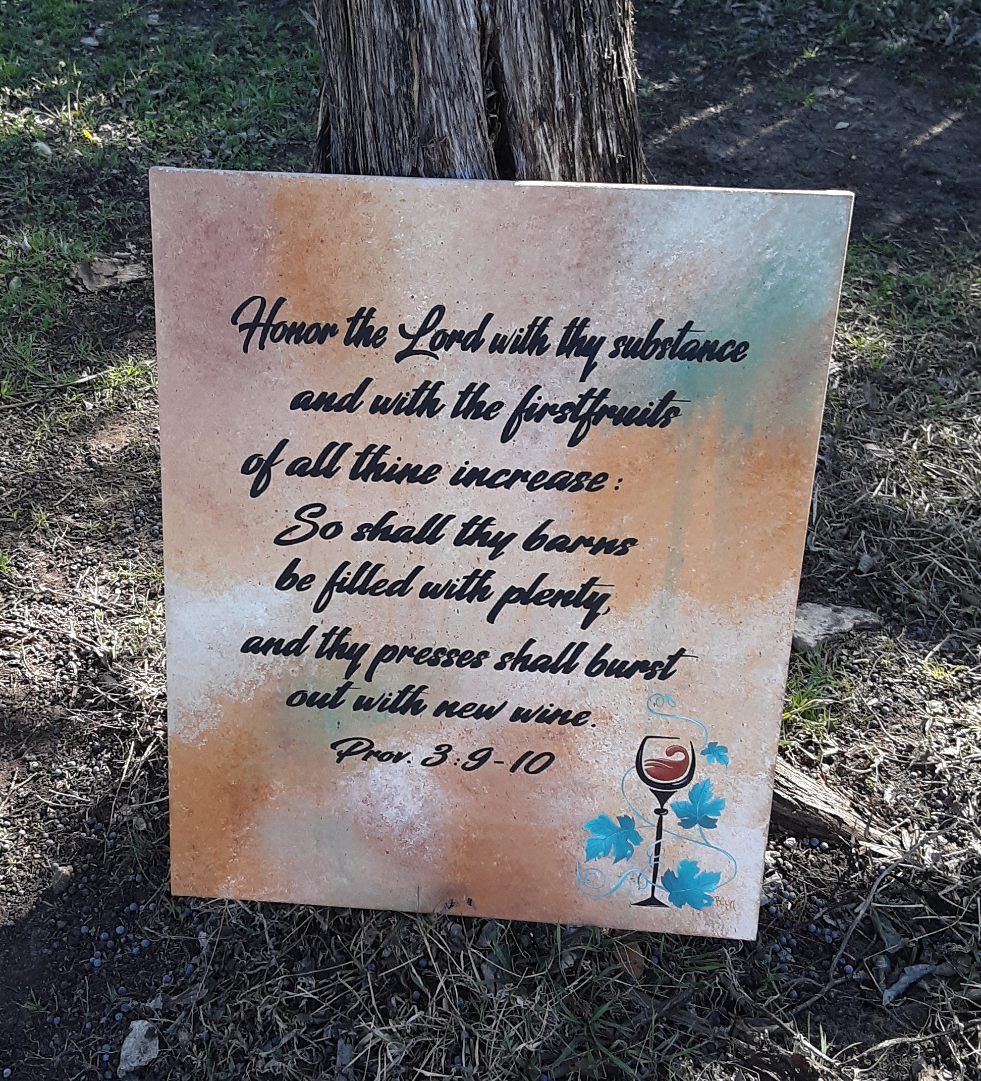 Decorative sign with biblical text and wine illustration on a natural background